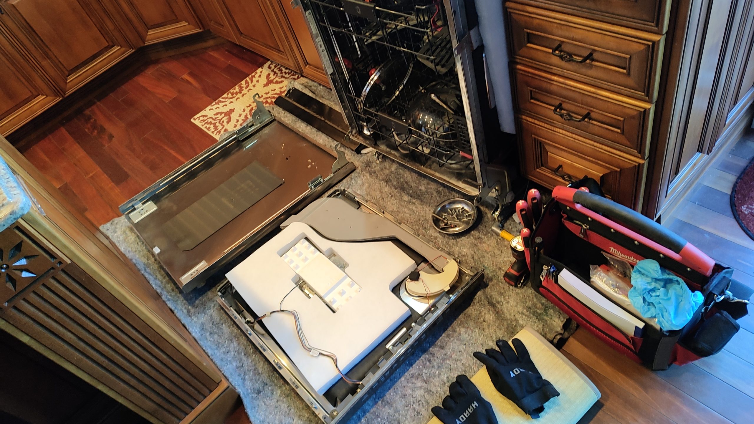 Dishwasher repair service with technician inspecting a built-in dishwasher