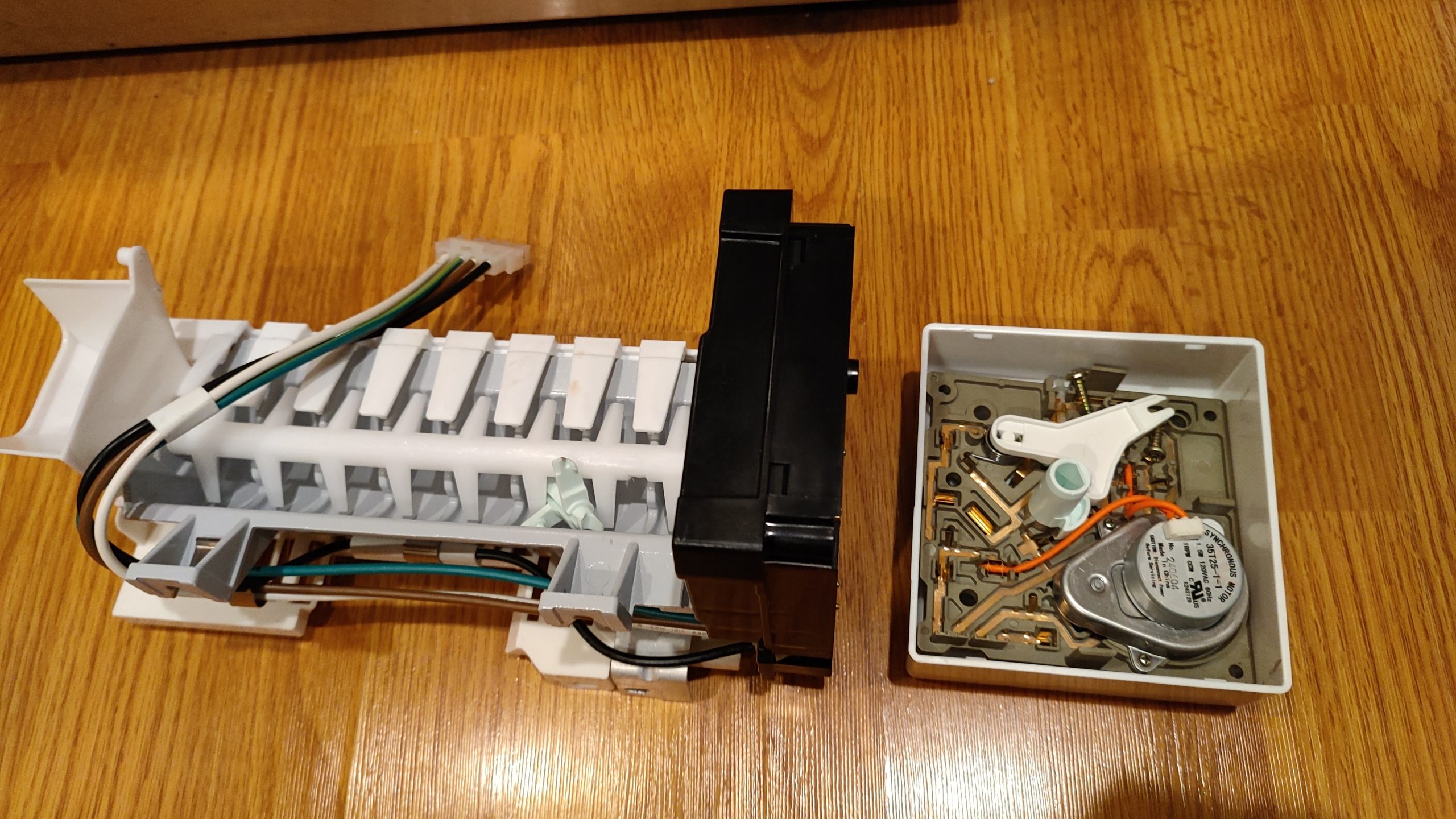 Disassembled refrigerator ice maker assembly during diagnosis and repair