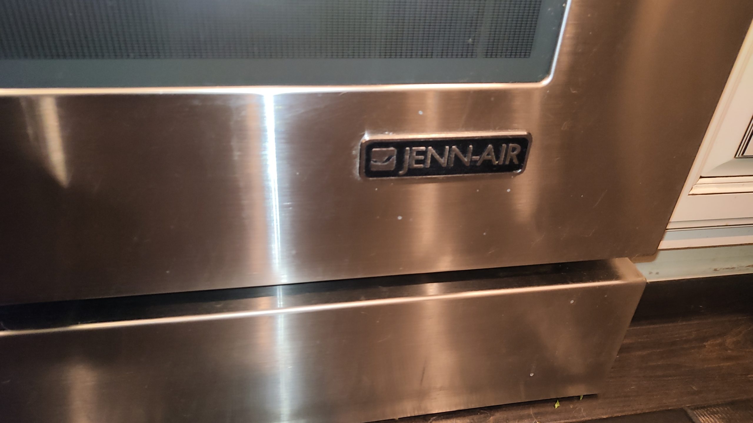 Close-up of the JennAir badge on the stainless steel gas range.