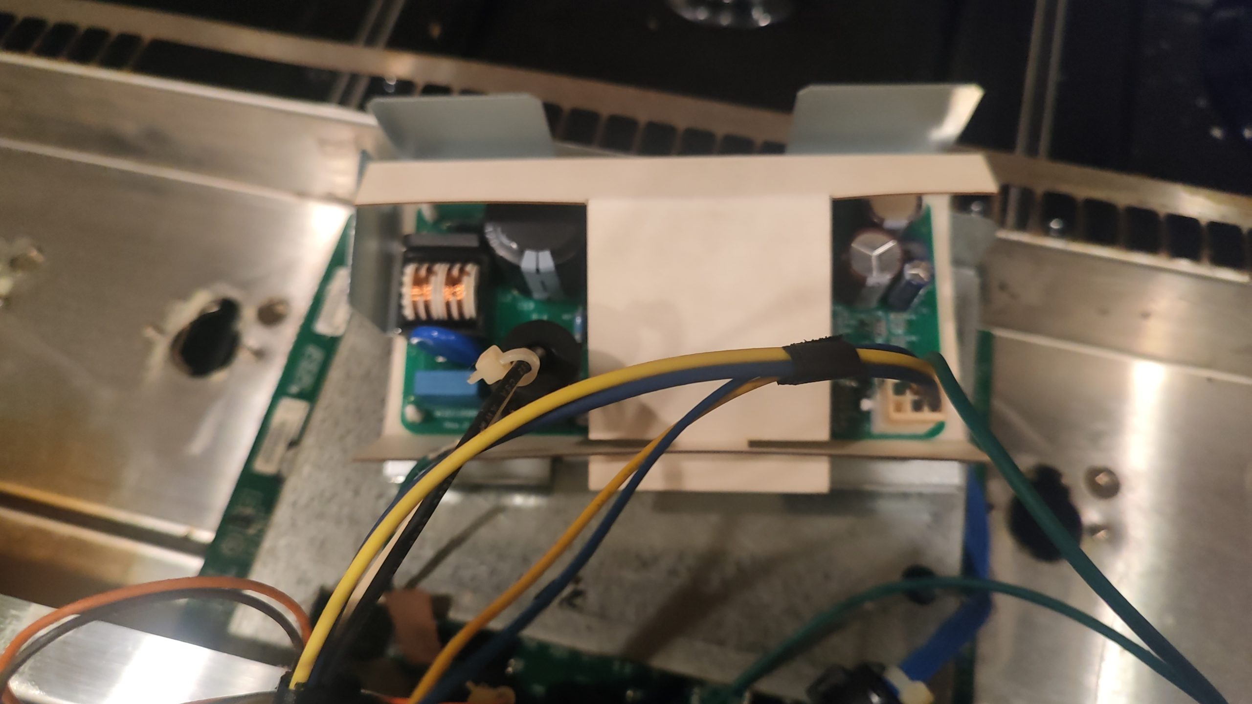 Low-voltage power supply board relocated behind the front panel of a JennAir gas range.