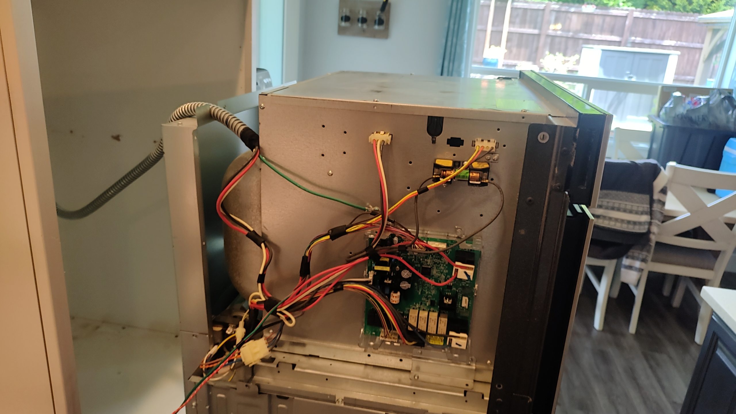 Exposed wiring and control board inside a Whirlpool WOC97ES0ES02 during microwave door repair