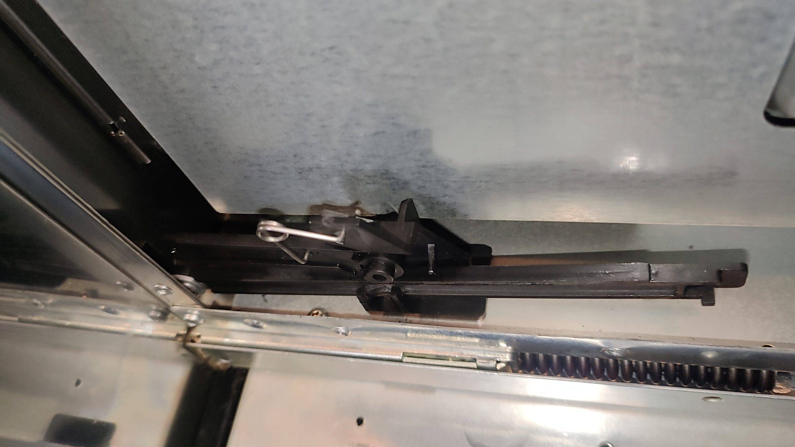 Close-up of the microwave door sliding arm bracket and spring mechanism on a Whirlpool WOC97ES0ES02