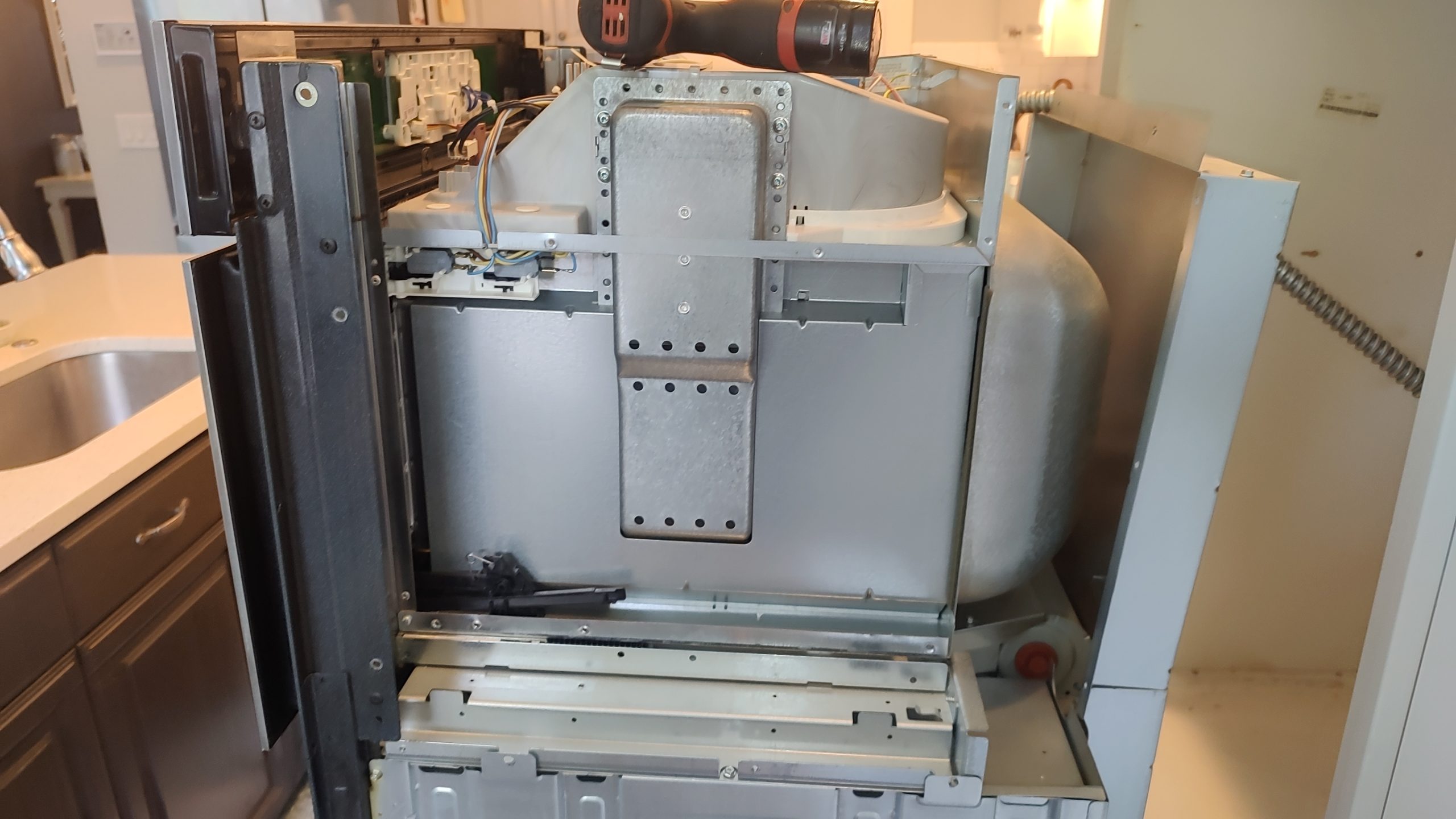 Whirlpool WOC97ES0ES02 with the side panel removed to access the microwave door hinge mechanism