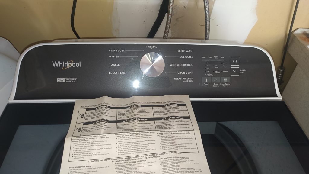 Whirlpool WTW6157PW0 top-load washer with the service diagnostic sheet placed on the lid